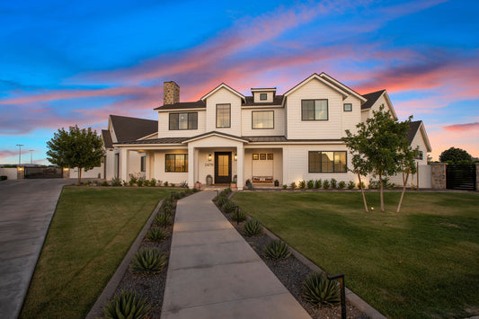 Luxury custom home exterior at twilight with warm interior lighting, stone chimney, and landscaped front walkway in Utah